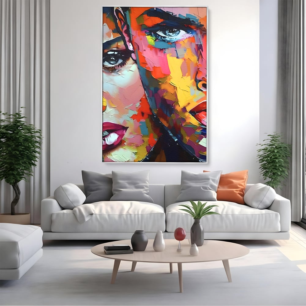 Tablou canvas cu tablou canvas cu chipuri in culori vibrante, in rama de aluminiu argintiu, pe perete intr-un living